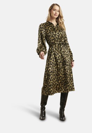 Donna che indossa un vestito di lunghezza media con stampa leopardata, maniche lunghe e cintura in vita, abbinato a stivali neri al ginocchio con tacco.