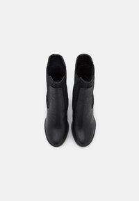 Bottines noires en cuir lisse dotées de panneaux latéraux élastiques et d'un petit talon empilé, avec un bout arrondi et des détails de surpiqûres.