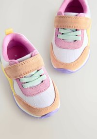Baskets de sport colorées avec une tige en tissu blanc, des accents en suède rose, des lacets menthe et une semelle violette. Sangle Velcro pour un ajustement sécurisé.
