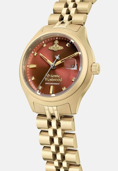 Reloj dorado con caja redonda, esfera de gradiente marrón, índices dorados y ventana de fecha. Cuenta con una atrevida pulsera de eslabones metálicos.