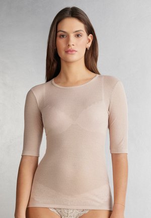 Licht beige geribbelde langemouwen top met een ronde hals en een getailleerd ontwerp. Zachte textuur en iets doorschijnend materiaal.
