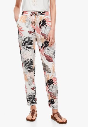 Women’s high-waisted pants with pink, black, and beige tropical leaf print, paired with brown sandals and a white top.