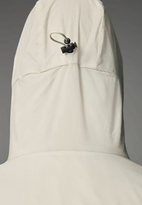 Light beige hoodie with textured fabric, featuring a unique adjustable toggle cord at the back of the hood for a secure fit.