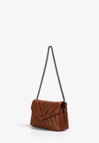 Bolso de cuero marrón acolchado con solapa tipo sobre, tira de cadena negra y pequeño emblema de calavera metálica en la parte frontal.