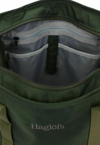 Borsa di stoffa verde con interno zip, dotata di un rivestimento grigio chiaro, una piccola tasca con zip e scomparti organizzativi per oggetti.