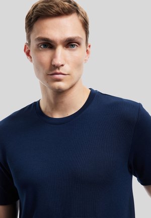 T-shirt ribbed blu navy con scollatura rotonda, maniche corte e design aderente. Texture liscia e dettagli minimi.