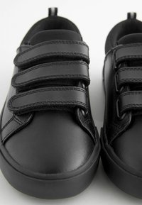 Czarne skórzane sneakersy z trzema paskami na rzep, zaokrąglonym noskiem i teksturowaną gumową podeszwą. Gładkie wykończenie z przeszyciami.