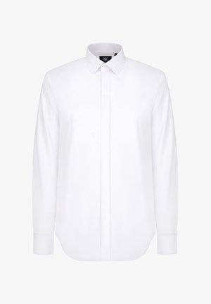 Biała koszula z długim rękawem, wykonana z gładkiego materiału, z zaostrzonym kołnierzykiem, zapięciem na guziki z przodu oraz zaokrąglonym dołem i mankietami zapinanymi na guziki.