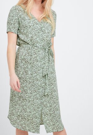 Vestido de manga corta, estilo envolvente, en verde claro con un patrón floral en toda la prenda, tejido texturizado y un cinturón con lazo en la parte delantera.