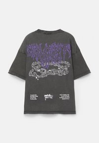 Grafisches schwarzes Oversized-T-Shirt mit lila Text und Kettenmuster auf dem Rücken. Zerschlissener Saum und weiche Baumwolltextur.