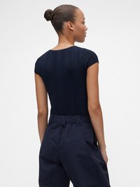 Σουτιέν σε μπλε ναυτικό χρώμα με ριγέ ύφασμα και κοντά μανίκια, με στρογγυλή λαιμόκοψη και κουμπιά στο πίσω μέρος, σε συνδυασμό με παντελόνι σε σκούρο μπλε ναυτικό χρώμα και ψηλή μέση.