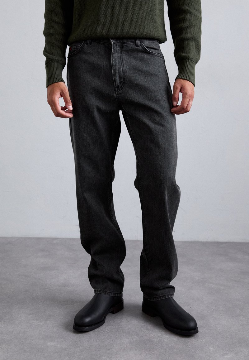 Dark grey denim jeans with a regular fit, featuring a classic five-pocket design. Paired with smooth black ankle boots.