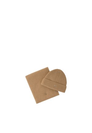 Cappello invernale marrone a coste con risvolto e sciarpa abbinata, entrambi con piccoli loghi ricamati su sfondo bianco.