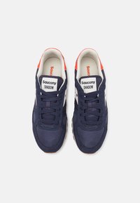 Marinblå sneakers med mesh- og semsket skinn, med hvite detaljer, en gummisåle og fremtredende merking på tungen og sidene.