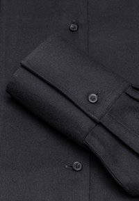 Schwarzes gewebtes Shirt mit Knopfdetail, ausgestattet mit umgeschlagenen Manschetten und Knopfleiste, strukturiertem Stoff und kontrastierenden schwarzen Knopfakzenten.