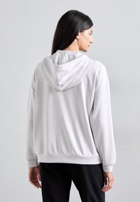Sweatshirt cinza claro com capuz e um corte descontraído, apresentando uma textura macia, punhos canelados e um bolso canguru na frente.