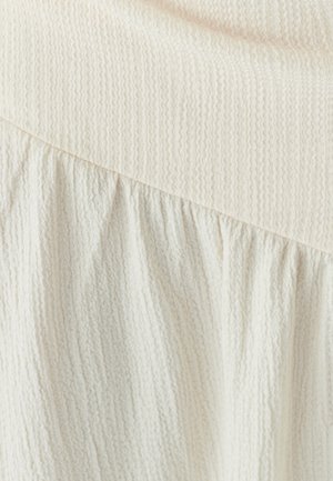 Light cream textured fabric with a ribbed top and gathered bottom, featuring soft folds and a smooth transition between sections.