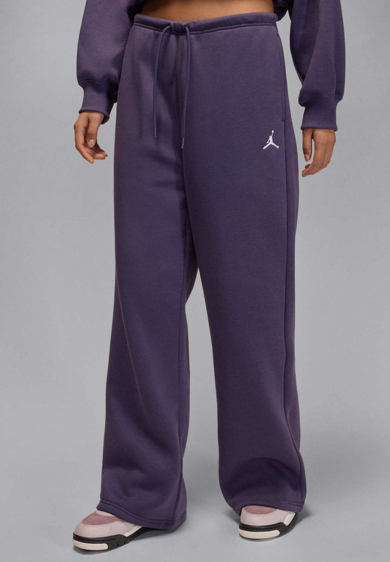 Paarse joggingbroek van zacht katoen met een trekkoord in de taille, brede pijpen en een klein wit Jordan-logo bij de heup. Gecombineerd met sneakers.