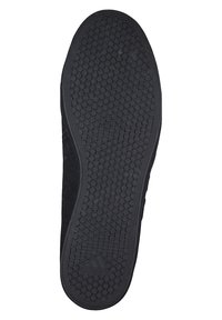 Suela de zapato de goma negra con una superficie texturizada que presenta patrones circulares y un logotipo de Adidas grabado cerca del talón.