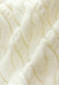 Model de tricot de culoare crem, cu cabluri mari și texturate. Lână moale și pufoasă, cu un finisaj neted și un aspect confortabil.