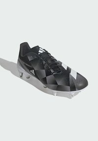 Crne nogometne kopačke s geometrijskim uzorkom, teksturirani sintetički gornji dio, crne vezice i bijeli detalji. Ima plastične čavliće za bolju vuču.