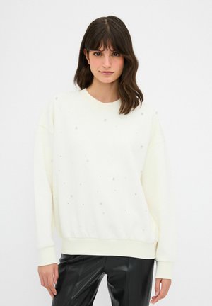 Witte oversized sweatshirt met versieringen, met een ronde hals en geribbelde manchetten. Gecombineerd met zwarte, glanzende neplederen broek.
