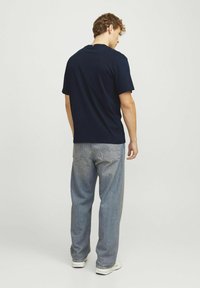 Marinblå bomull t-shirt med kort ärm, kombinerad med ljusblå raka jeans. Åtsittande design med rund halsringning och avslappnad passform.