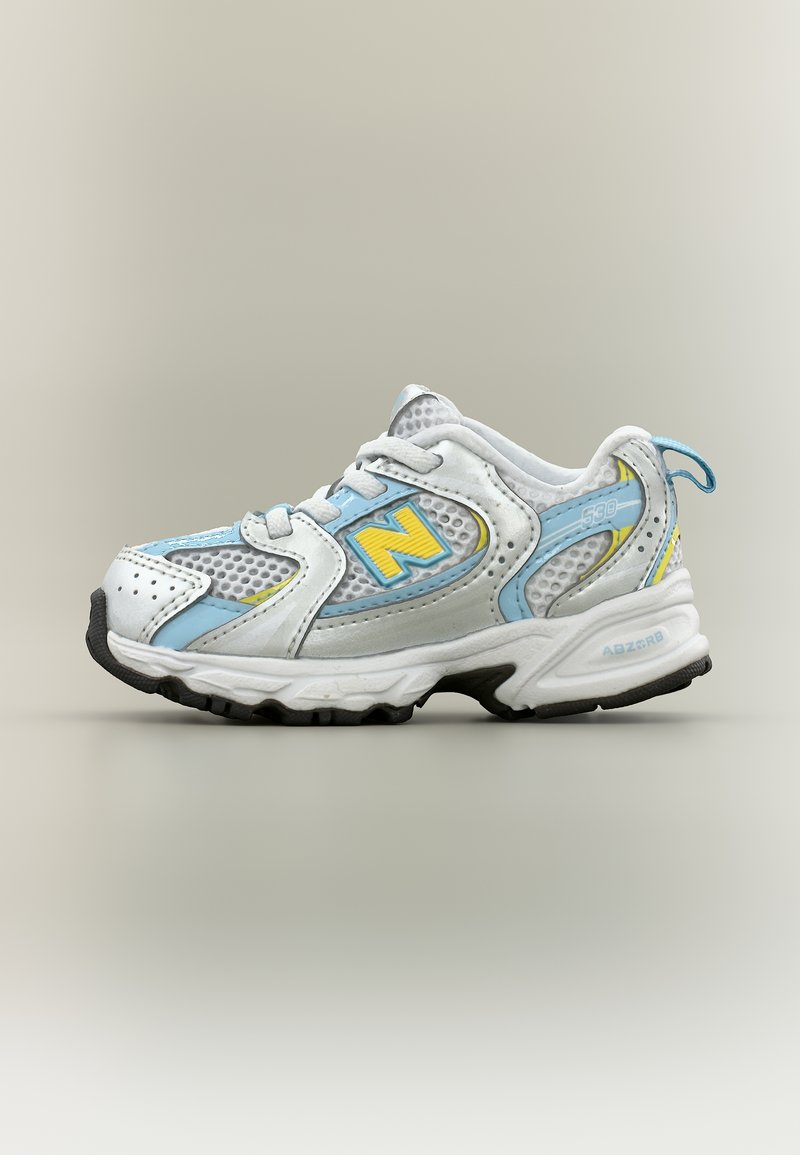 Λευκό και ανοιχτό μπλε αθλητικό παπούτσι New Balance 530 με κίτρινες λεπτομέρειες, πάνελ από δίχτυ και μαύρη σόλα με πέλμα, πλαϊνή όψη.