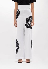 Pantaloni bianchi a gamba larga con grandi stampe di rose nere, design a vita alta, realizzati in tessuto leggero, con zip laterale nascosta.