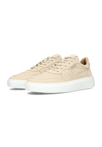 Zapatillas de ante beige con suela de goma blanca, con un diseño de cordones y detalles perforados en la punta para ventilación.