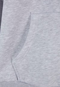Szürke kapucnis pulóver, puha, texturált anyagból, kenguruzsebbel és bordázott szegéllyel. A design egyszerű, díszítő minták nélkül.