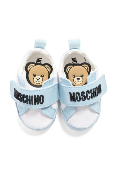 Chaussures pour bébé blanches et bleu clair avec des visages d'oursons à l'intérieur et "MOSCHINO" brodé en noir sur les brides.