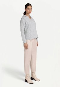 Ljusblå stickad tröja med V-ringning och strukturerat mönster, kombinerad med beige avsmalnande byxor och krämfärgade ankelboots med klack.