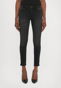 Mustat slim-fit farkut, joissa on teksturoitu sivuosa. Ominaisuuksiin kuuluu klassinen viisi-taskuinen muotoilu, vyölenkit ja lievä nypytyshelmavari.