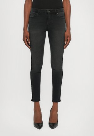 Zwarte slim-fit jeans met een textuurdetail aan de zijkant. Heeft een klassieke vijf-pocket ontwerp, riemlussen en een licht rafelige zoom.