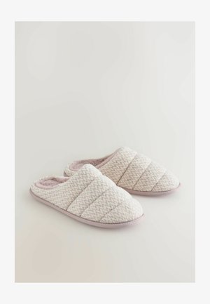 Mehki roza in bele prešitih copate z mehkim notranjim podplatom in zaobljenim prstom, ki imajo teksturirano zunanjost in ravne podplate.