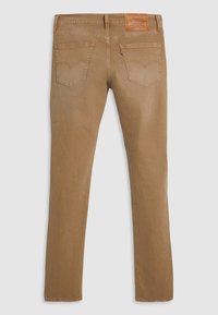 Jean en denim marron à coupe droite, avec deux poches arrière, des détails de couture subtils et une étiquette en cuir sur la ceinture.