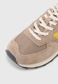 Brune ruskind og mesh sneakers med cremefarvede snørebånd, gule accenter og en tekstureret overflade. Sort gummisål for godt fodfæste.