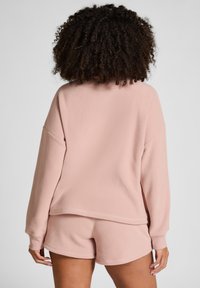 Lichtroze sweatshirt met een losse pasvorm en verlaagde schouders, gecombineerd met bijpassende shorts, met een zachte textuur en minimale naden.