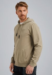 Hoodie khaki en tissu doux, avec une poche kangourou, une capuche à cordon de serrage et un logo imprimé sur la poitrine. Bordures côtelées aux poignets et à l'ourlet.