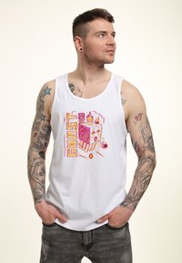 Hvid tanktop med et farverigt pixeliseret grafik med ordet "GHAST" og flammedetaljer. 100% bomuldsmateriale, løs pasform og ærmeløs design.