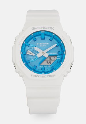 G-Shock Uhr mit einem weißen Harzarmband, blauem Zifferblatt und silbernen Akzenten. Verfügt über ein digitales Display, eine Lichtfunktion und mehrere Tasten zur Anpassung.