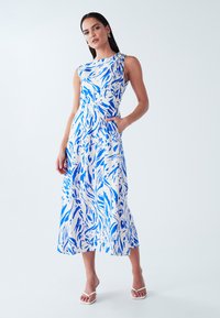 Blue and white patterned dress with a one-shoulder design, a fitted waist, and side pockets; smooth fabric, knee-length skirt.
