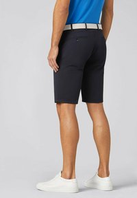 Shorts marins avec une coupe slim, dotés d'une ceinture tissée beige. Le matériau semble lisse, avec une coupe classique et des détails minimaux, associés à des chaussures blanches.