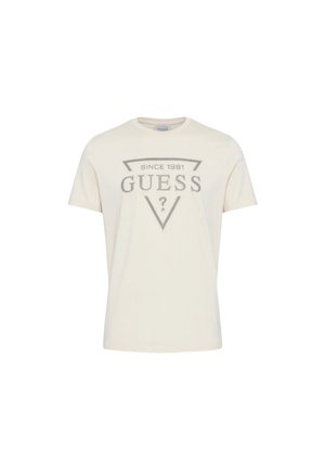 T-shirt à manches courtes écru avec le logo "GUESS" et le texte "Since 1981" à l'intérieur d'un triangle pointant vers le bas sur le devant.