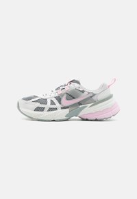Zapatilla deportiva blanca y gris con parte superior de malla, acentos en rosa y una suela gruesa y texturizada. Presenta un diseño con patrón y una lengüeta.