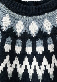 Zbliżenie na kołnierz wełnianego swetra z wzorem w białe, czarne i jasnoniebieskie geometryczne kształty oraz paski.