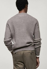 Gray ribbed knit sweater with long sleeves and a round neck, paired with olive green pants featuring back pockets and buttons.