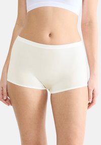 Krämfärgad hipsterunderkläder i en mjuk, elastisk tyg med ett vitt band vid midjan och sömlösa kanter.