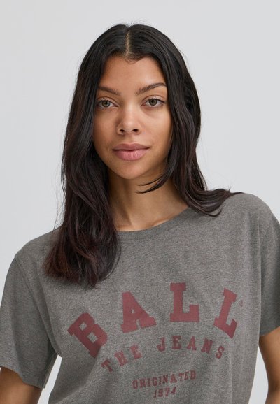 Grå kortærmet t-shirt med rød tekst, der siger "BALL THE JEANS ORIGINATED 1974." Blødt bomuldsstof med en afslappet pasform.